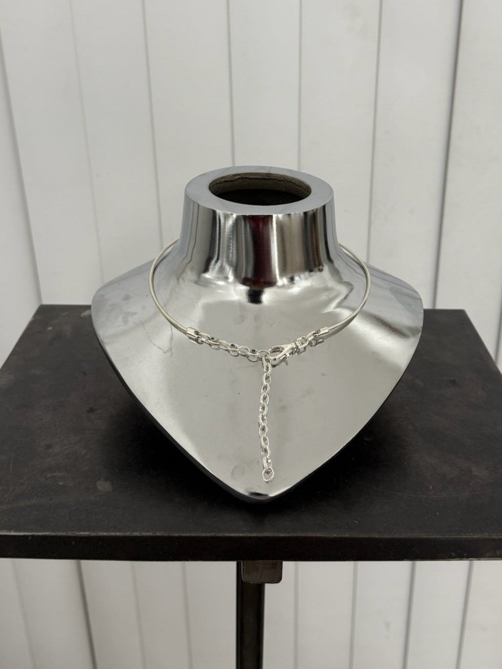 Silver choker necklace on a mannequin bust against a white background