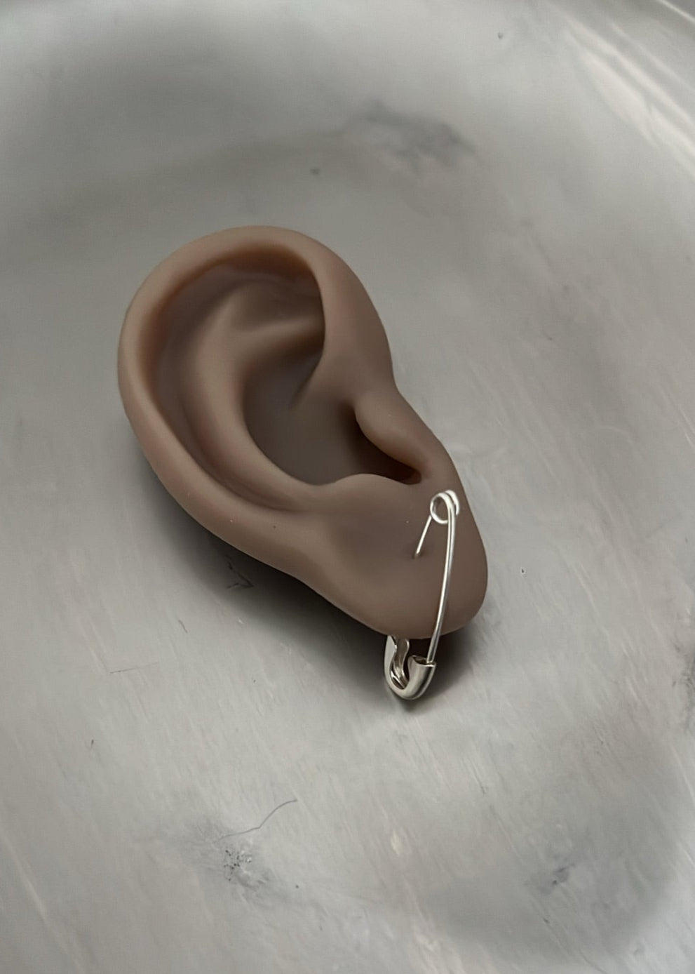 Silicone ear with a safety pin on a white background