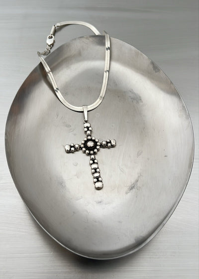 Silver cross pendant necklace on a metallic surface
