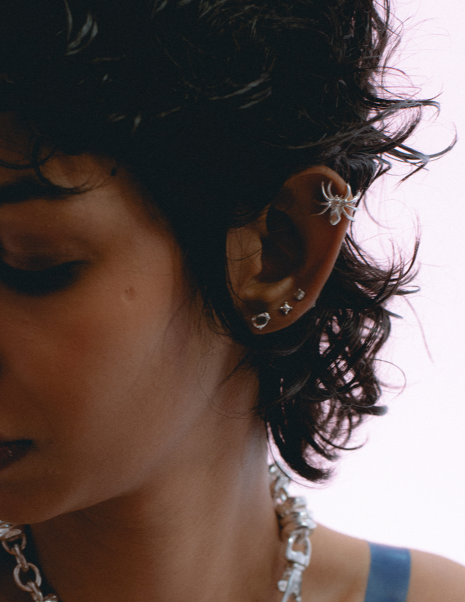 Web-inspired stud earring design in silver . on model