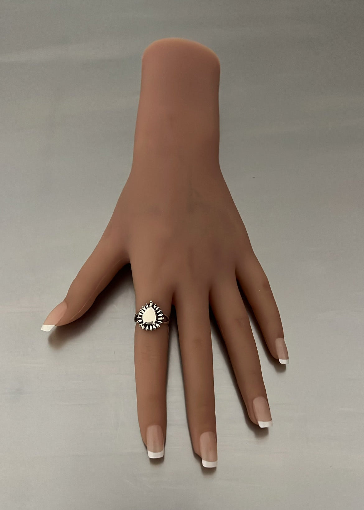 Mannequin hand wearing a ring on a neutral background